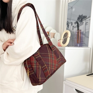 Detailed macro view of the retro wool plaid shoulder bag featuring deep red and green patterns