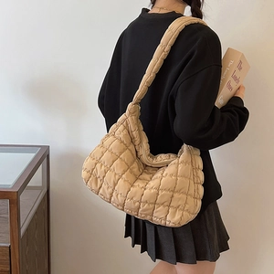Quilted beige puffer hobo bag shown from a side angle on a model for scale and style