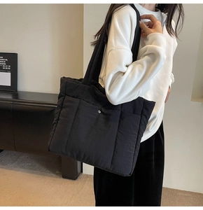 Detail view of large black quilted tote bag with padded texture and snap button closure