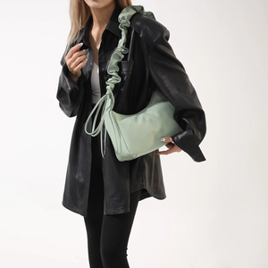 Sac hobo vert sauge avec bandoulière plissée porté par un mannequin en cuir noir