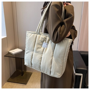 Detailed view of cream quilted puffer tote bag in lightweight nylon with minimalist label