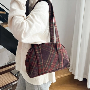 Detailed close-up of a vintage red tartan wool shoulder bag featuring a classic plaid pattern
