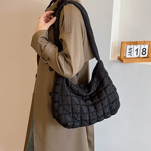 Detail of black quilted puffer fabric texture on a minimalist women shoulder tote bag