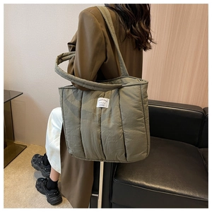 Detail of army green quilted puffer tote bag with white square label shown on shoulder