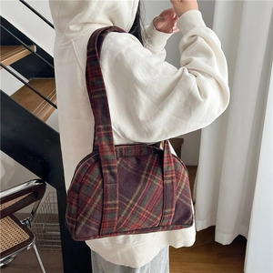 Detail shot of the vintage plaid woolen texture and metal zipper on this shoulder bag
