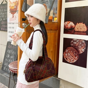 Winter plaid wool shoulder bag in red and green worn with a cozy white sweater
