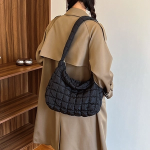 Minimalist black quilted shoulder bag with puffy texture worn by model in a stylish setting
