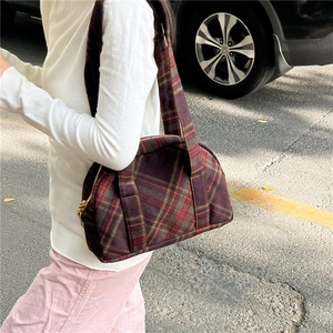 Close-up of vintage plaid shoulder bag in red and green wool fabric on person
