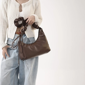 Détail d'un sac hobo en cuir PU marron foncé avec une large bandoulière plissée élégante