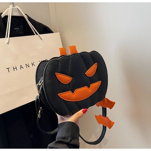 Detail of pumpkin-shaped crossbody bag with orange bat charms and face patches