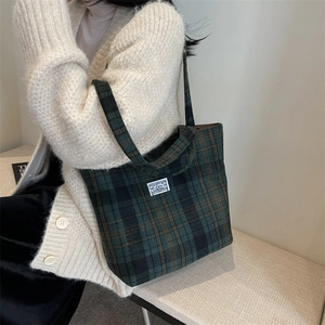 Detail of green plaid tote bag in textured wool fabric with vintage brand patch