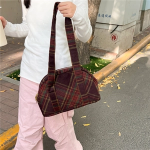 Close-up of retro plaid wool handbag with wine red and green checkered fabric texture
