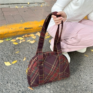 Detail of vintage purple wool plaid handbag with zipper and twin handles on city street