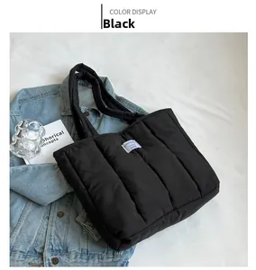 Close-up of black quilted down tote bag with woven logo label on white cloth background