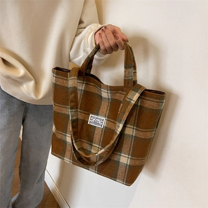 Detail of winter plaid tote bag in brown wool fabric with shoulder strap and handles