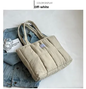 Detail of a quilted beige tote bag with woven brand logo and puffy nylon texture