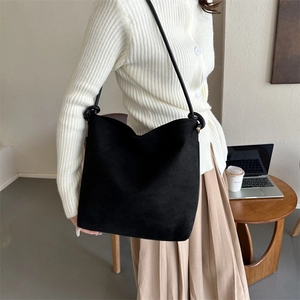 Detail einer minimalistischen schwarzen Wildleder-Tote-Bag mit modischem Knotenschultergurt