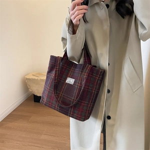 Detail of premium plaid tote bag in vintage burgundy and green wool fabric on a trench coat