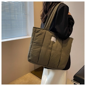 Close-up of olive green quilted tote bag with soft puffer texture and brand tag