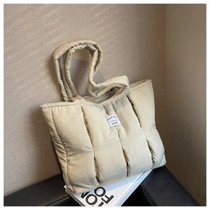 Detailed view of beige quilted tote bag with square stitching and white brand label