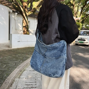 Vista stradale di una borsa hobo in denim blu lavato indossata da una modella all'aperto