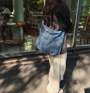 Dettaglio di una grande borsa a tracolla in denim blu con tessuto patchwork e texture retrò