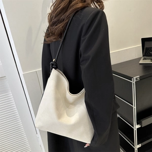 Detail der cremefarbenen Canvas-Tasche mit schwarzen geknoteten Trägern im Büro-Stil