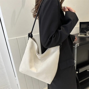 Detail der minimalistischen cremefarbenen Hobo-Tasche mit schwarzen geknoteten Riemen