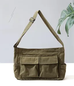 Detail of army green canvas crossbody bag featuring front flap pockets and wide strap
