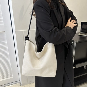 Detail der minimalistischen cremefarbenen Hobo-Tasche mit schwarzem Knotengurt-Design