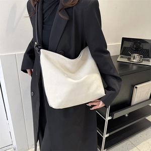 Detail einer minimalistischen beigen Wildledertasche mit geknotetem schwarzen Trageriemen