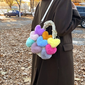 Vue de rue extérieure d'un sac bandoulière en peluche coloré en forme de cœur avec poignée