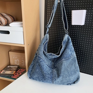 Dettaglio del tessuto in denim blu lavato della borsa a tracolla con ampia cinghia