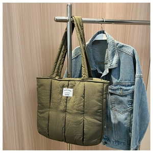Detail view of olive green quilted puffer tote bag with square stitching and fabric label