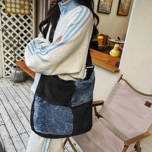 Dettaglio della grande borsa a tracolla in denim con patchwork nero e blu su modella