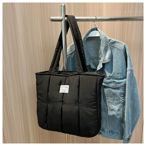 Detailed view of black quilted puffer tote bag with brand patch and padded shoulder straps