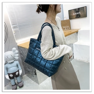 Dettaglio della borsa tote trapuntata blu scuro che mostra il materiale lucido imbottito