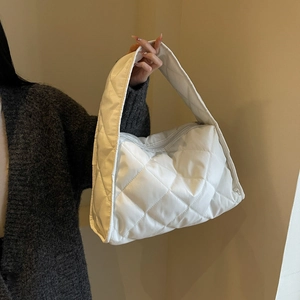 Close-up of white quilted puffer shoulder bag showing soft nylon texture and diamond stitching