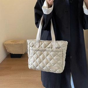 Detail der gesteppten Tragetasche in Beige mit praktischer Vordertasche und Logo-Patch