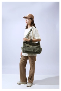 Model wearing a large army green canvas messenger bag showing its size and cargo style