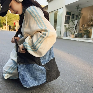 Dettaglio della borsa tote patchwork in denim con ampia tracolla nera in tessuto