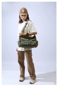 Olive green canvas messenger bag with large front pockets and adjustable wide black strap
