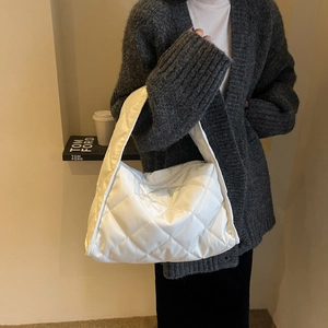 White quilted tote bag with padded nylon texture shown from a side view on a model
