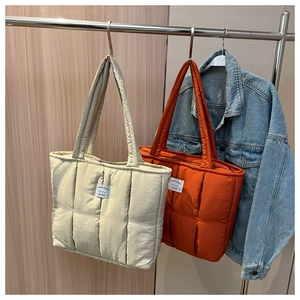 Detail of quilted puffer tote bags in cream and caramel with premium stitching
