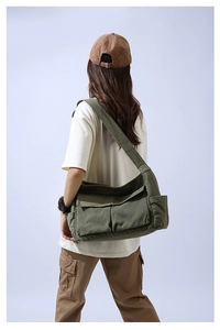 Close-up of olive green canvas messenger bag with large flap pockets and wide shoulder strap