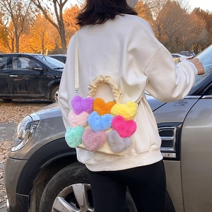 Gros plan détaillé d'un sac à bandoulière en peluche beige avec des cœurs multicolores