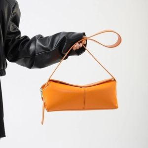 Dettaglio della borsa a spalla in pelle PU arancione brillante tenuta da una modella