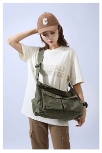 Detail view of durable green canvas crossbody bag featuring functional pockets and strap