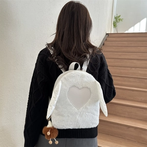 Close-up of a white plush backpack featuring a heart patch and long rabbit ear decorations