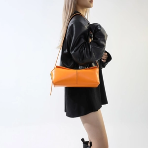 Vista laterale della borsa baguette arancione acceso in pelle PU indossata dalla modella